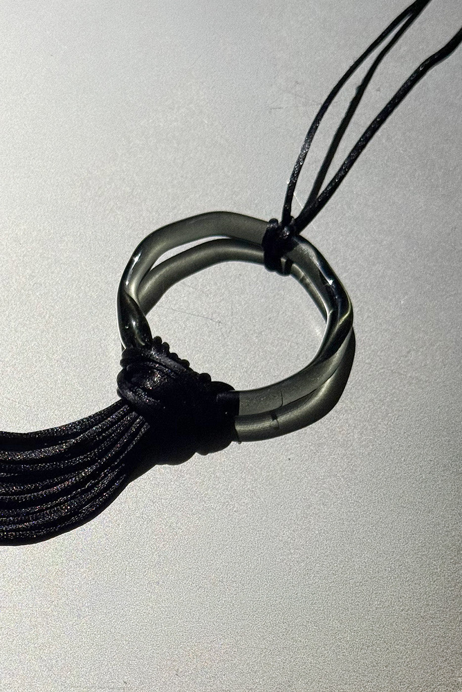 Close-up of handcrafted borosilicate glass ring black with black satin cord fringe, Beryeni El Jaleo